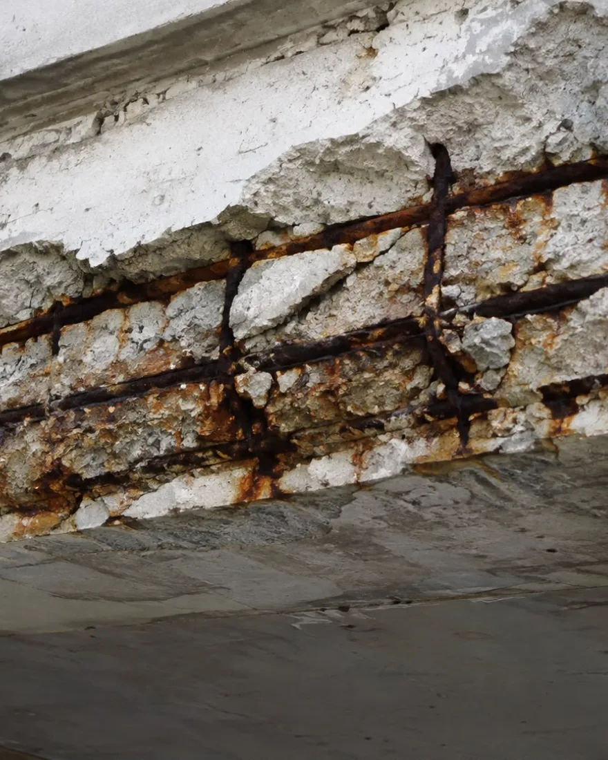 Viga de concreto com o cobrimento desprendido e a armadura de aço exposta e corroída