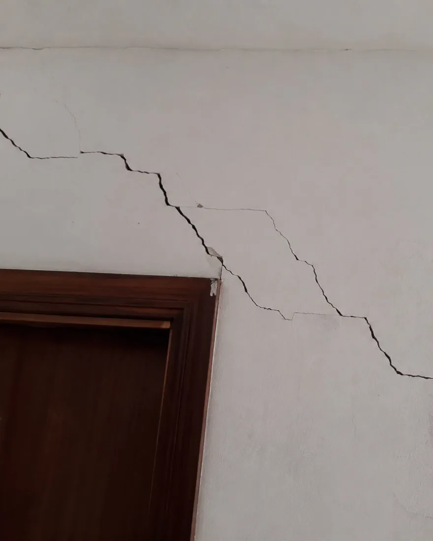 Trinca escalonada em parede interna, descendo do teto até a janela e passando pelo batente da porta