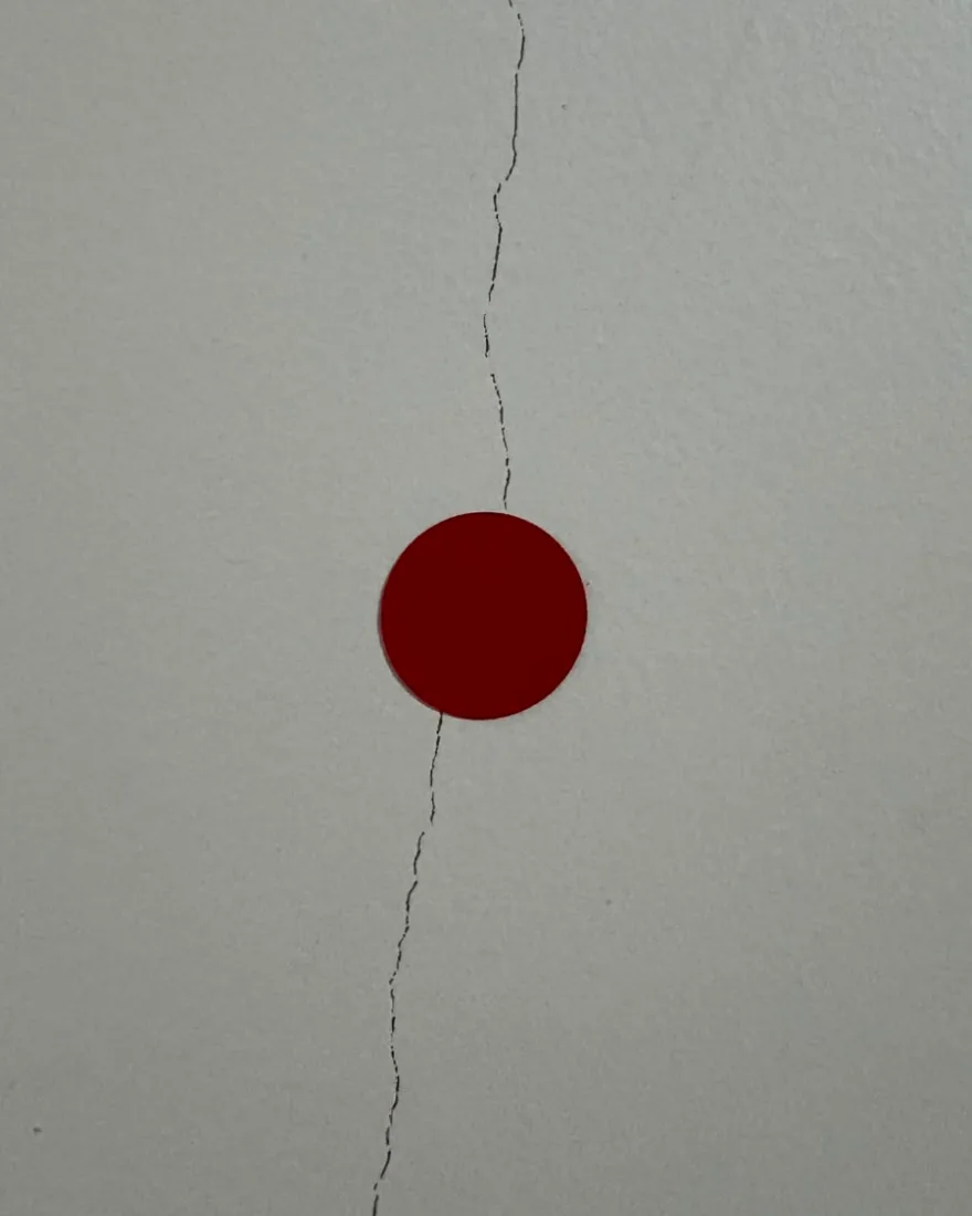 Fissura vertical em parede interna, marcada com adesivo circular vermelho durante a vistoria